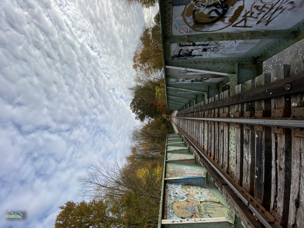 flipped image of cloudy blue sky on left and train tracks on right