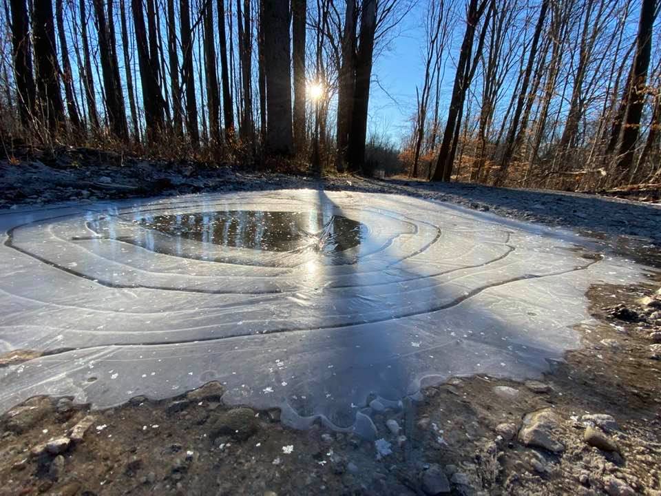 A reflected sunrise on an icy puddle