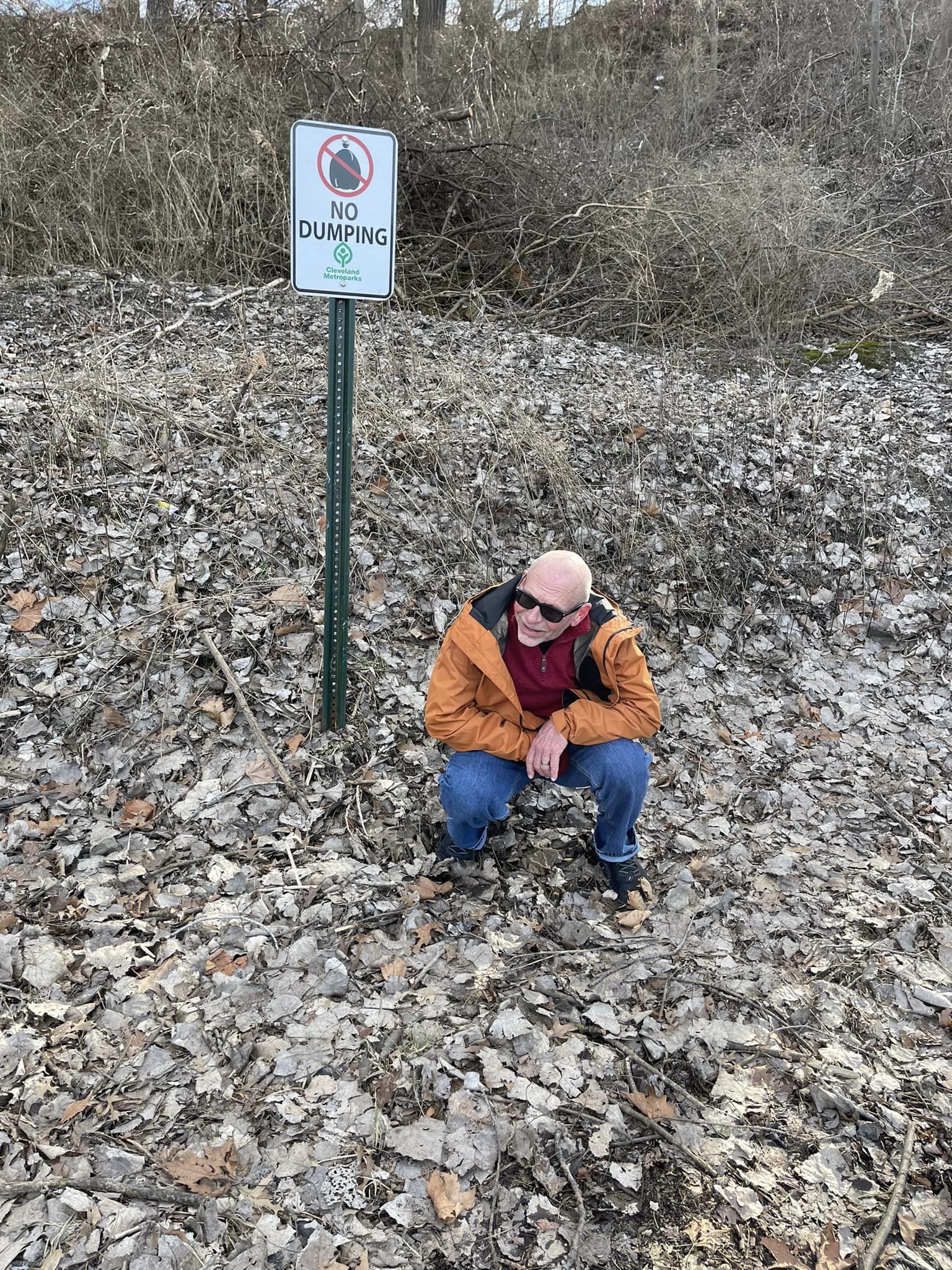 Opa Runs crouching by a no dumping sign
