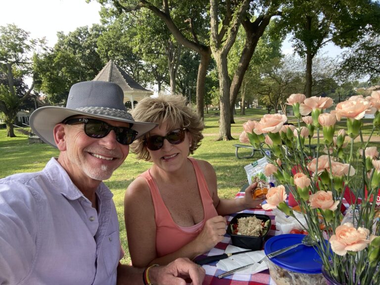 OpaRuns and Sherry Carnahan eating at picnic table with bouquet of carnations