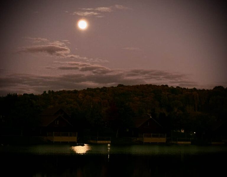 Moon in twilight sky reflecting on a lake